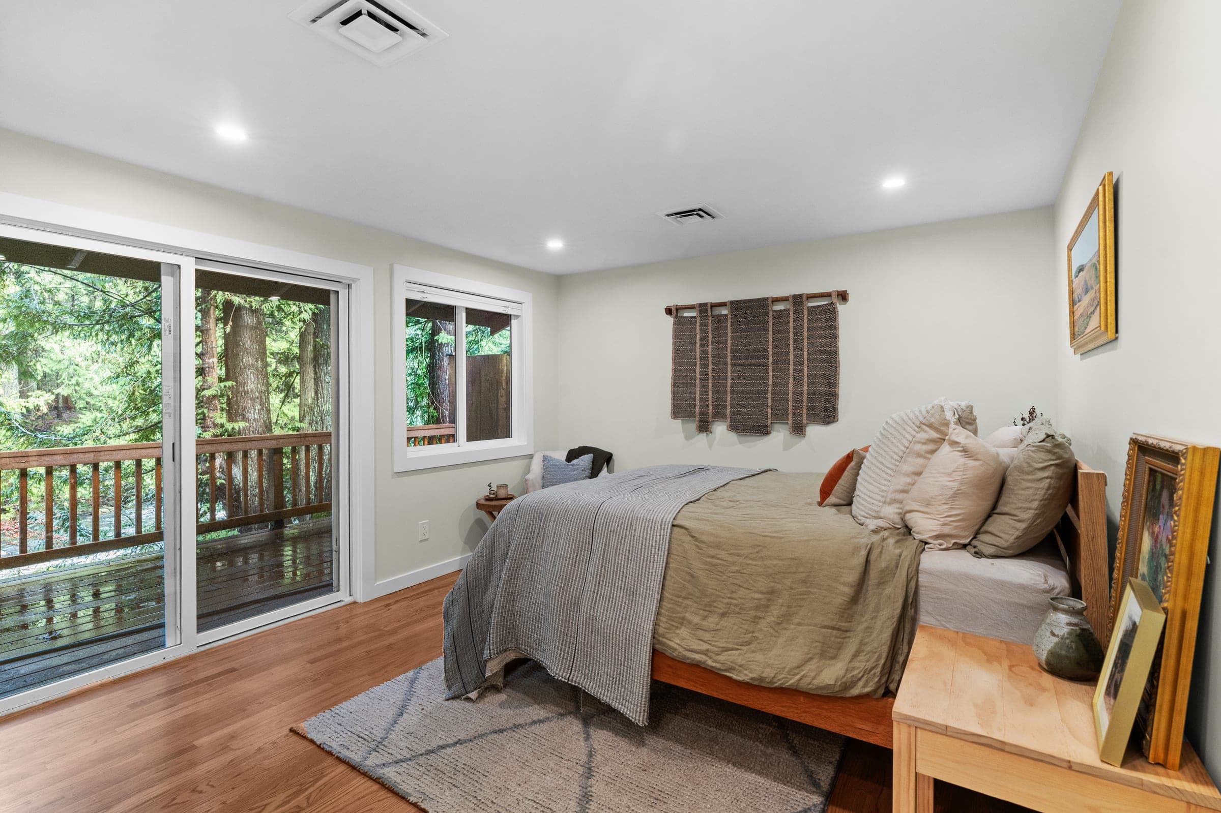 River Front Master Suite bedroom with a glass slider opening to the deck and river trees, North Bend